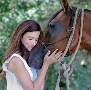 a woman petting a horse
